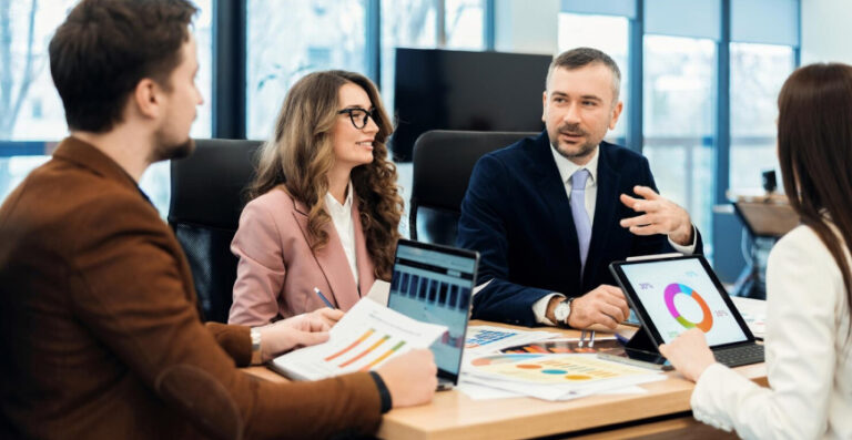 Empresários discutindo estratégias com gráficos e planilhas durante reunião de contabilidade estratégica empresarial.