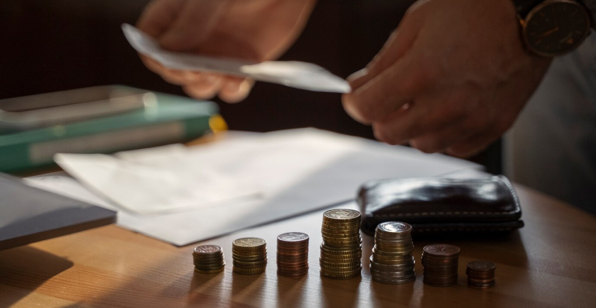 Empresário analisando moedas e documentos sobre mudanças tributárias no Brasil